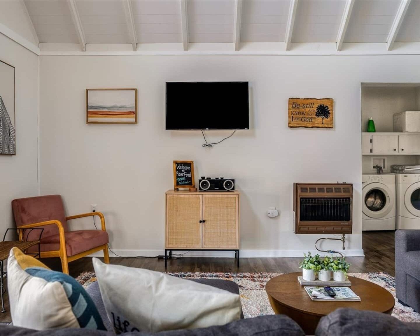 Een woonkamer met een televisie, radio, kast, stoel, bank en salontafel.