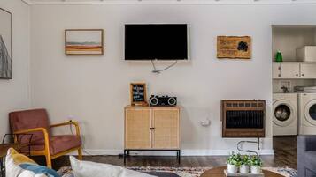 Een woonkamer met een televisie, radio, kast, stoel, bank en salontafel.