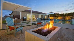 A backyard with a fire pit, outdoor seating, a pool, and a covered patio area. - Rolling Hills: Luxury Home, Heated Pool, Mtn Views (Desert Hot Springs)