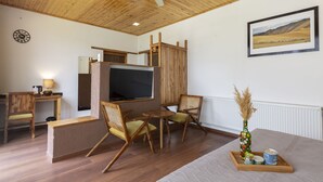 Une pièce chaleureuse, meublée de meubles en bois, dotée d’un téléviseur à écran plat, d’une horloge et d’un tableau représentant un paysage, encadré.