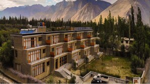 Un immeuble à plusieurs étages doté de balcons, entouré d’un paysage montagneux.