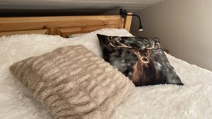 A bed with a fluffy white blanket and two pillows, one with a deer image and another plain. - 3-room duplex for 6 people with balcony and WIFI in L'Alpe d'Huez (Huez)