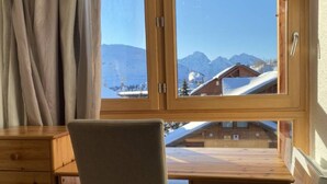 A wooden cabin with a large window offering a view of snow-covered mountains. - 3-room duplex for 6 people with balcony and WIFI in L'Alpe d'Huez (Huez)