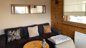 A cozy living room with a dark sofa, multiple cushions, a round wooden coffee table, and a decorative lantern. - 3-room duplex for 6 people with balcony and WIFI in L'Alpe d'Huez (Huez)