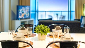 Une table à manger dressée avec des assiettes, des bols, des verres et une plante en pot.