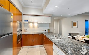 A modern kitchen with wooden cabinets, stainless steel appliances, and a granite countertop.