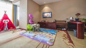 A child-friendly room with a play tent, a child-sized chair, a TV, and a desk. - Ming Hua Hotel (Aksu)