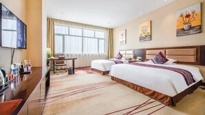 A hotel room with two beds, a desk with a TV, and artwork on the walls. - Ming Hua Hotel (Aksu)