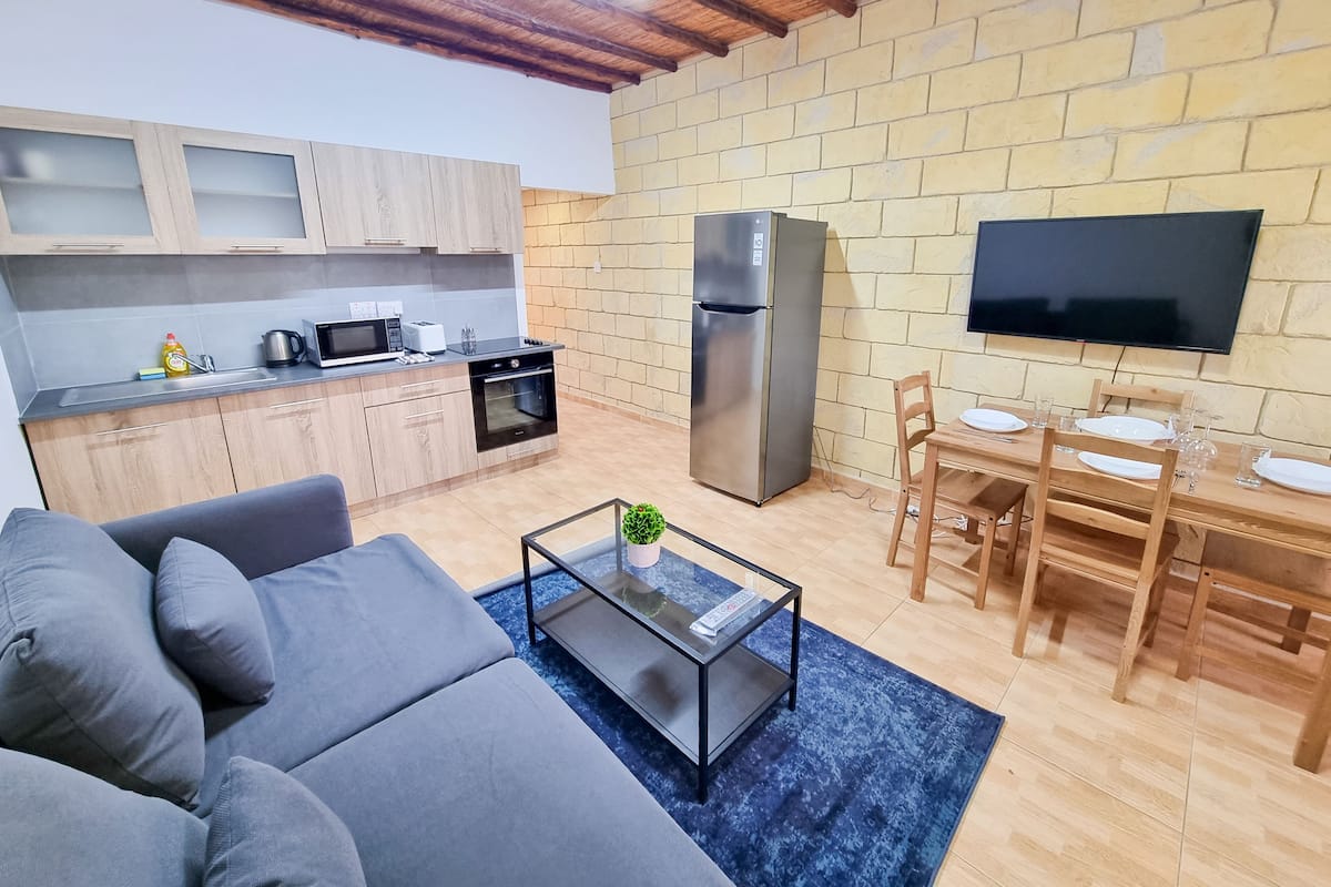 Eine moderne Küche mit Kühlschrank, Backofen und Mikrowelle. Es gibt einen Essbereich mit Tisch und Stühlen, sowie eine Wohnbereich mit Sofa und Couchtisch.