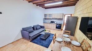 Un espace de vie compact comprenant un canapé, une table à manger et un coin cuisine.