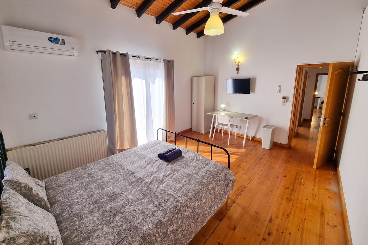 Ein Schlafzimmer mit Bett, Schreibtisch, Stuhl, Fernseher und Kleiderschrank.