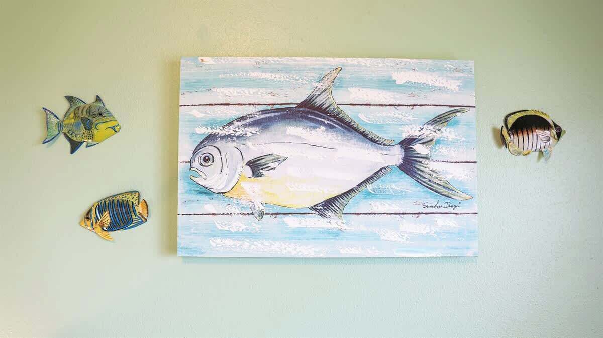 A painting of a fish on a wall with three smaller fish on either side.