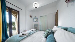 Un dormitorio con cama, mesita de noche, espejo, armario y vistas a través de un ventanal.