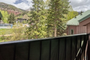 A mountain view with a cabin, a building with a green roof, and a parking area with vehicles. - Manitou Lodge 10 Hotel Room by Alpine Lodging Telluride (Telluride)