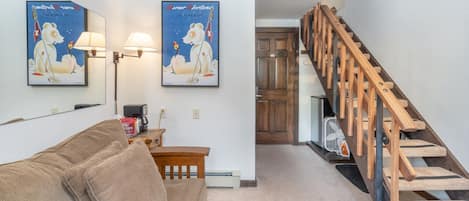 A living room with a sofa, two wall-mounted lamps, and a staircase.