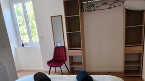 Une chambre à coucher avec un lit, une chaise rouge, une armoire et un miroir.