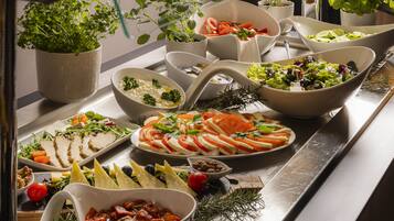 A buffet with various food items including sliced tomatoes, cheese, and salads.