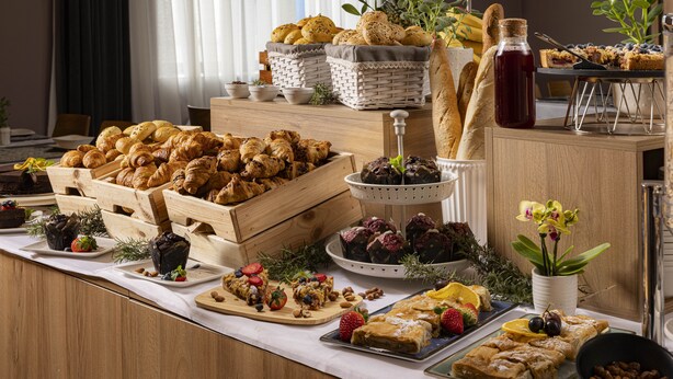 A buffet with various pastries, fruits, and a bottle of syrup.
