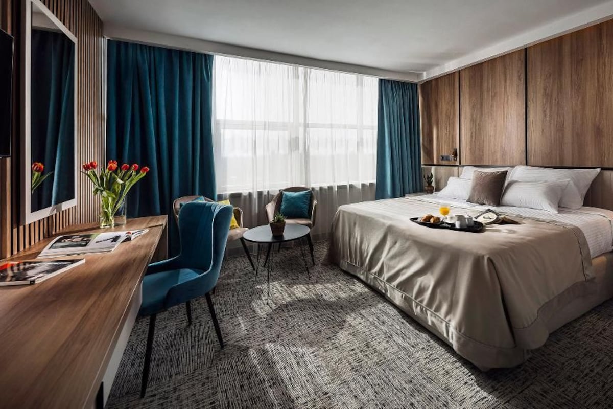Een hotelkamer met een bed, een bureau, een stoel, een klein tafeltje en een televisie.
