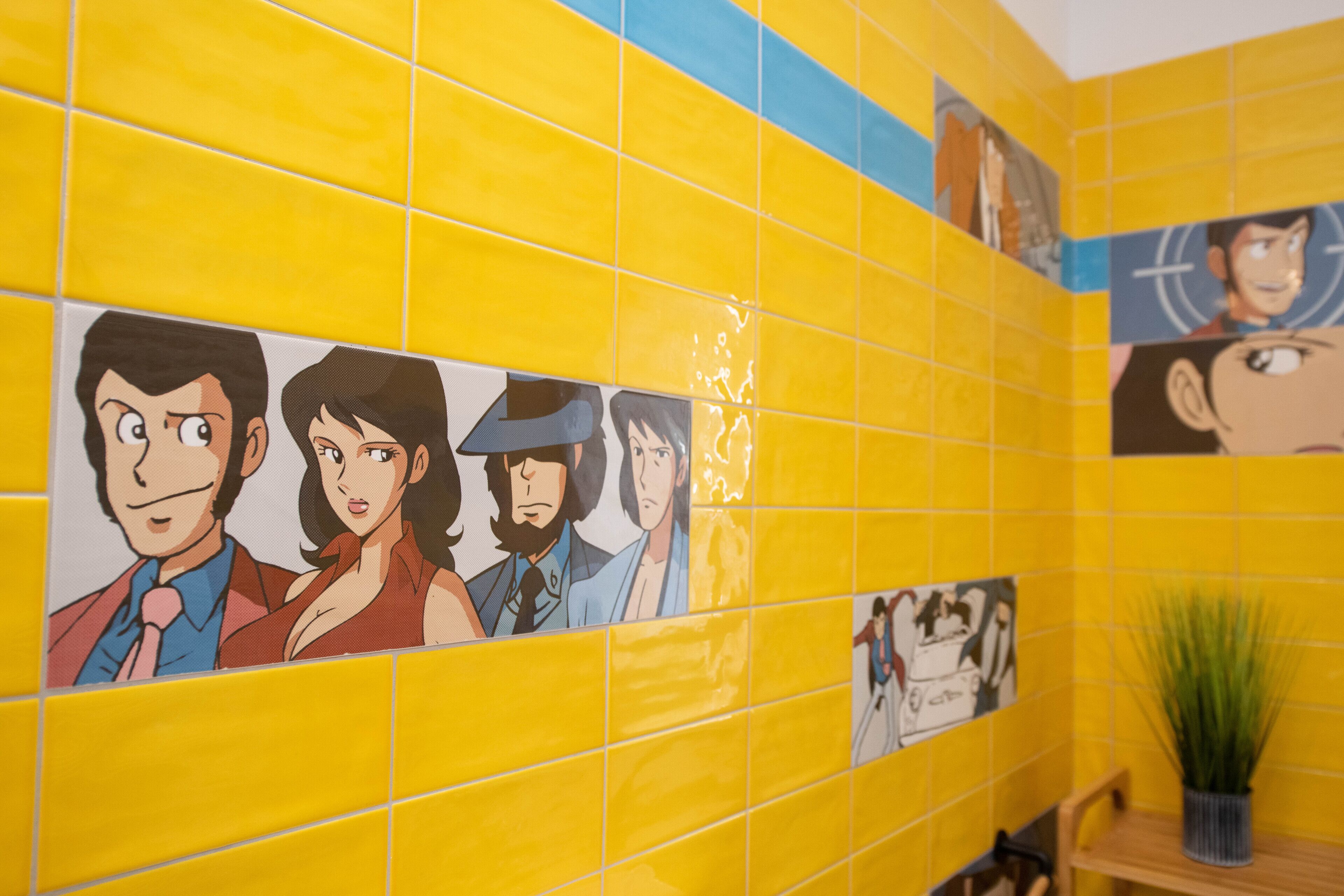 A bathroom with yellow tiles and cartoon character artwork on the walls.