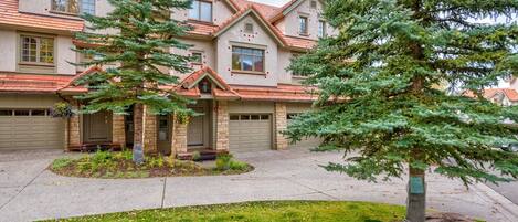A two-story house with a garage, a front porch, and a well-maintained lawn.