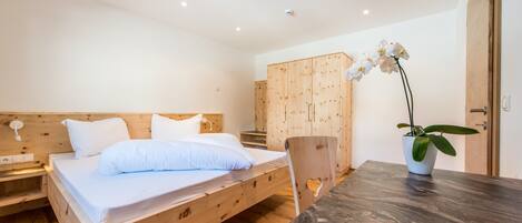 Un dormitorio con una cama de madera, una mesita de noche, un armario y una orquídea en maceta.