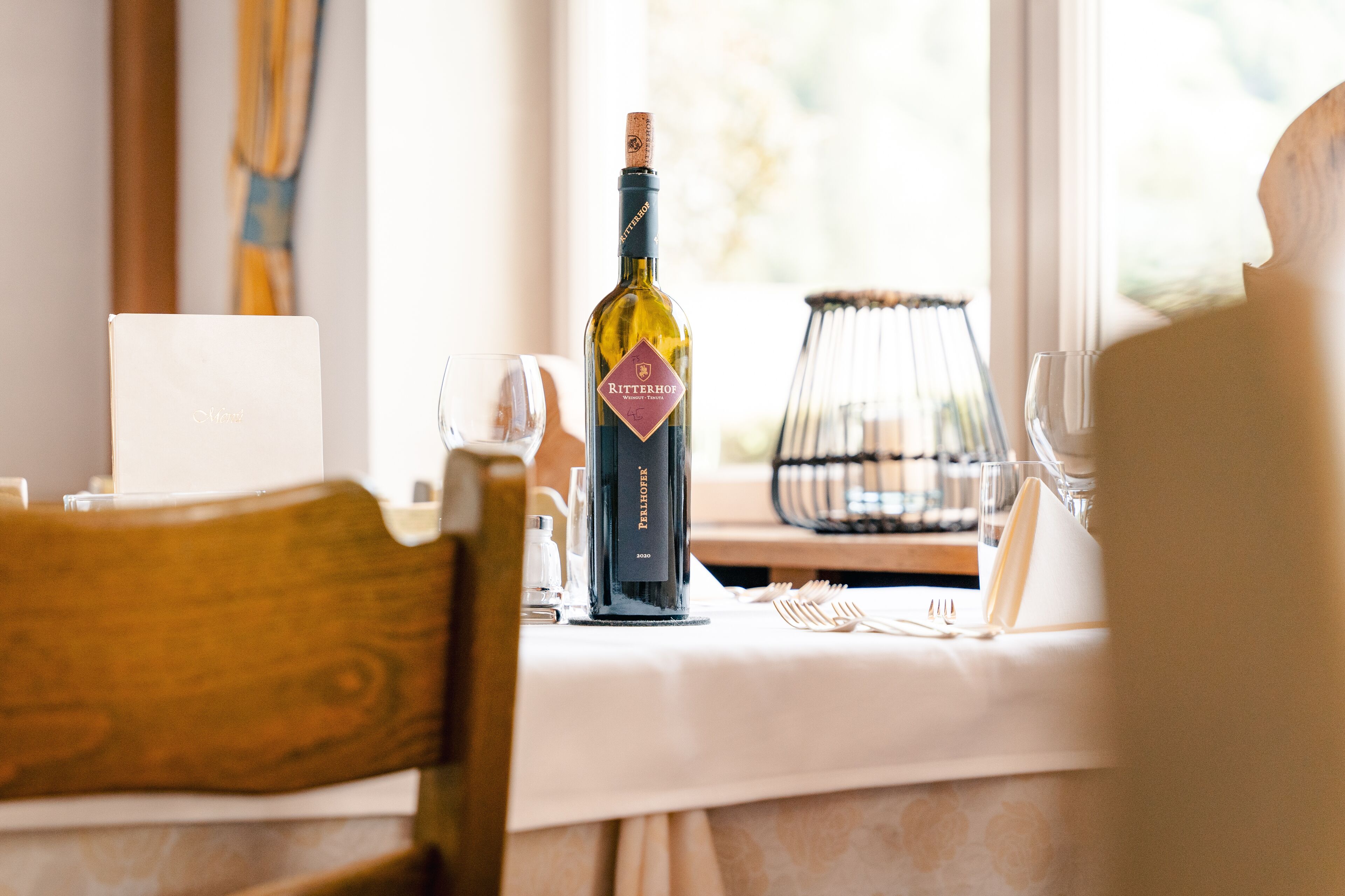 Una mesa dispuesta con una botella de vino, copas y cubiertos.