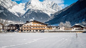 A hotel with multiple floors, balconies, and a view of snow-covered mountains. - Hotel Antholzerhof (Rasun Anterselva)