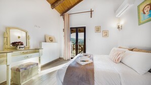 Une chambre à coucher comprenant un lit, une commode, un miroir et une fenêtre donnant sur l’extérieur.
