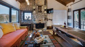 Un salon chaleureux avec une cheminée en pierre, un banc en bois et un canapé agrémenté de coussins.