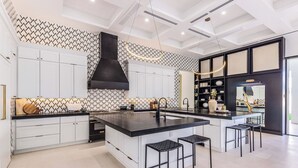 A modern kitchen with white cabinetry, a black island, and bar stools.