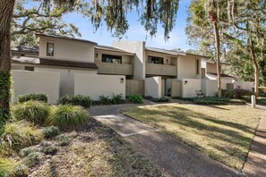 A modern multi-story residential building with a covered patio area, surrounded by landscaped gardens and mature trees. - Gorgeous Marsh Views from Spacious Villa - Beach One Mile Away! (Amelia Island)