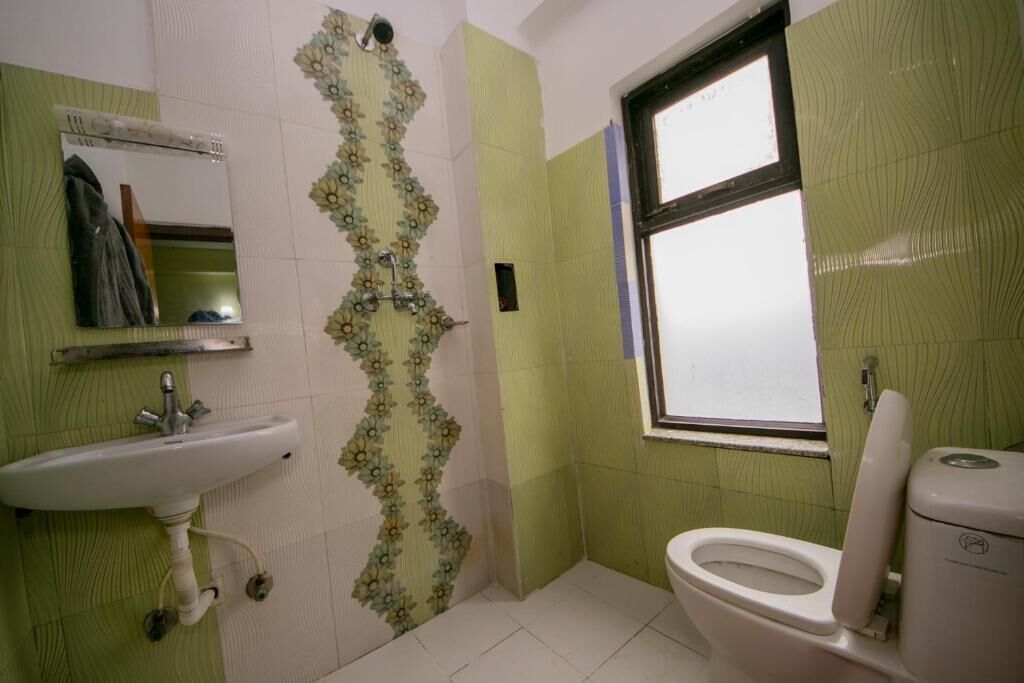 A bathroom with a sink, toilet, and a window.