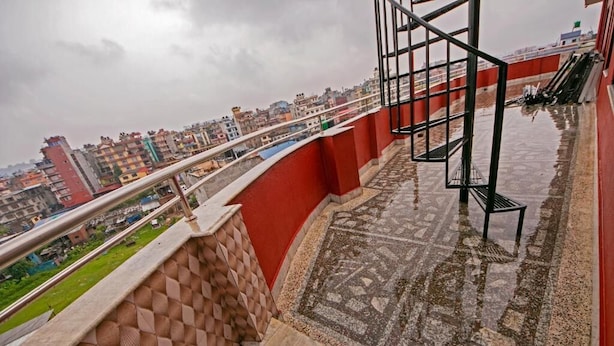 Terraço no telhado com piso estampado, guarda-corpo de metal e vista para o horizonte urbano.