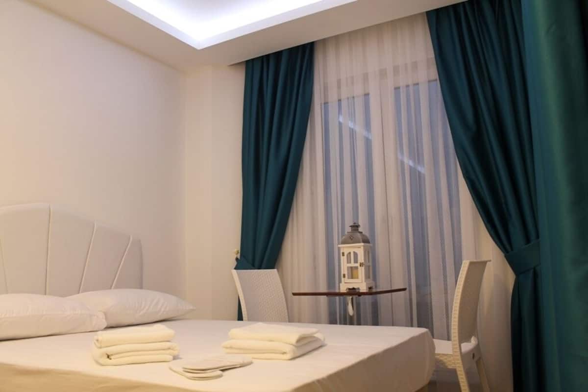 A hotel room with a bed, a small table with a lantern, and a chair.