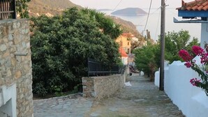 A narrow stone pathway leading uphill, flanked by white walls and lush greenery. - Demie and George House with stunning view (Γλώσσα)