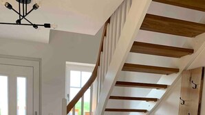 Eine moderne Treppe mit Holzboden und weißen Wänden, die zu einer oberen Etage führt.
