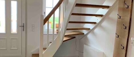 Una escalera moderna con escalones de madera y paredes blancas, que conduce a un piso superior.