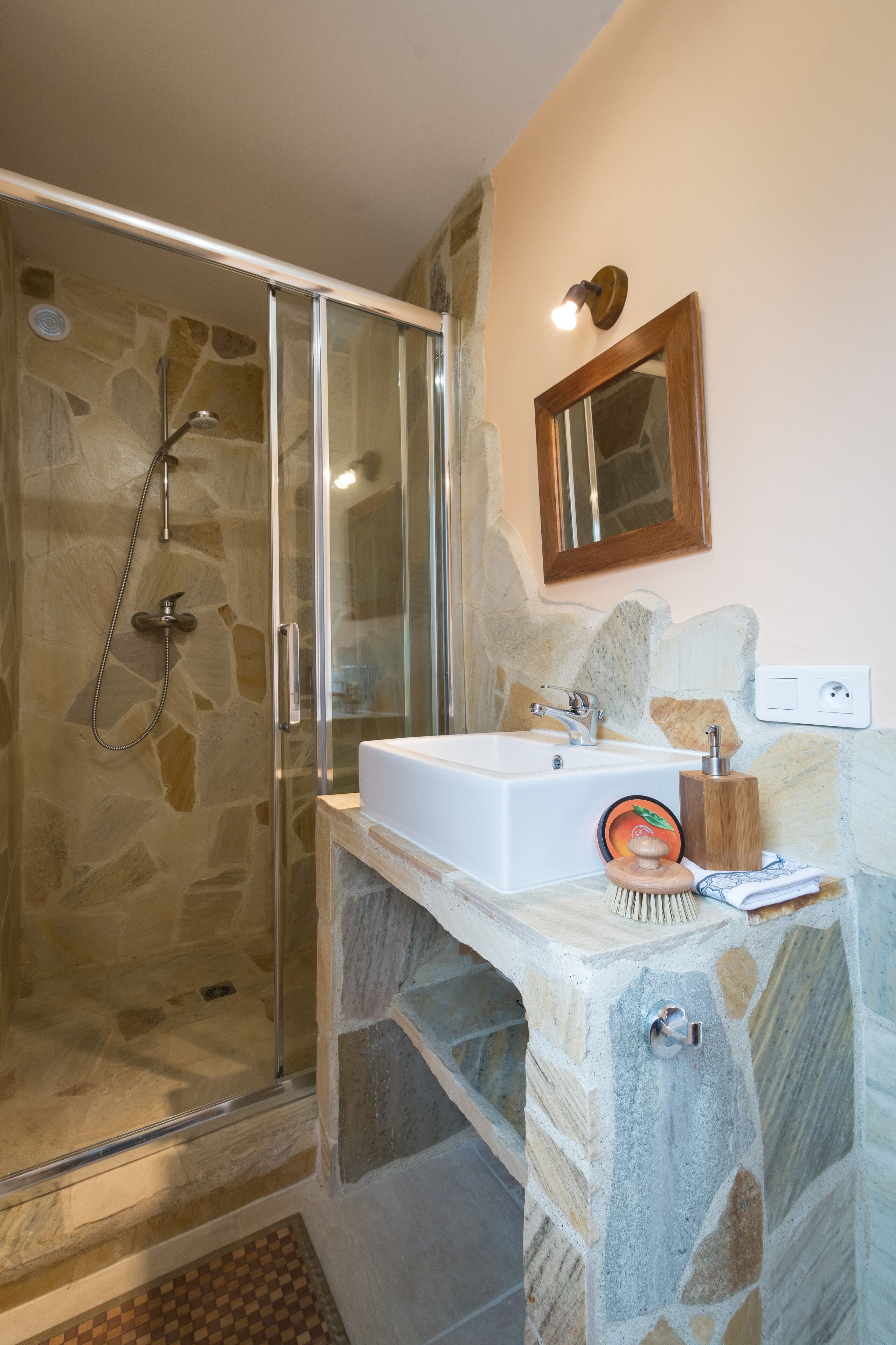 A bathroom with a glass-enclosed shower, a white sink, and a wooden vanity.
