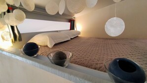 Ein Schlafzimmer mit Etagenbett, großem Fenster und dekorativen Papierlampen.