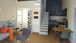 Ein modernes Apartment mit Wohnzimmer, Essbereich, Küche und einer Treppe zu einer oberen Ebene.