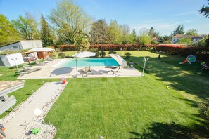 A backyard with a swimming pool, a patio with lounge chairs, and a well-maintained lawn.