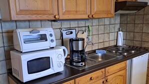 A kitchen with wooden cabinets, a microwave, a coffee maker, and a sink.
