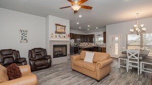 Ein geräumiges Wohnzimmer mit Ledersofas, einem Kamin und einem Essbereich mit einer Chandelier.