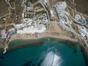 Vue aérienne d’une zone côtière avec une plage, des bâtiments et un port de plaisance.