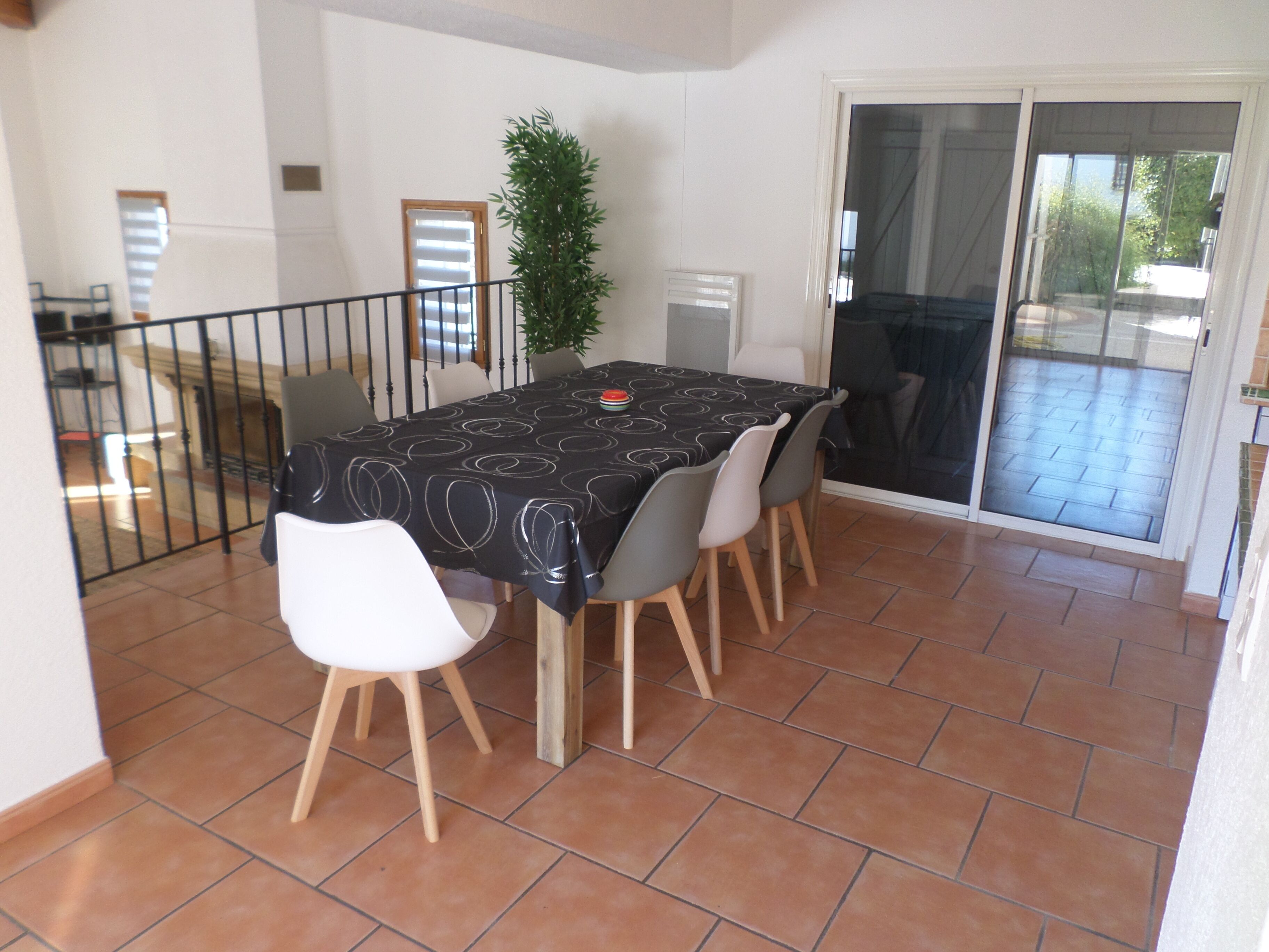 Un coin repas avec une table recouverte d’une nappe noire orn ée de motifs blancs, entourée de quatre chaises aux pieds en bois.