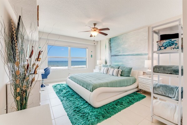 Relax in this serene bedroom with a large bed, nightstand, and dresser, offering a peaceful ocean view.