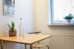 Une petite table avec une plante en pot, une bouteille transparente et un verre.