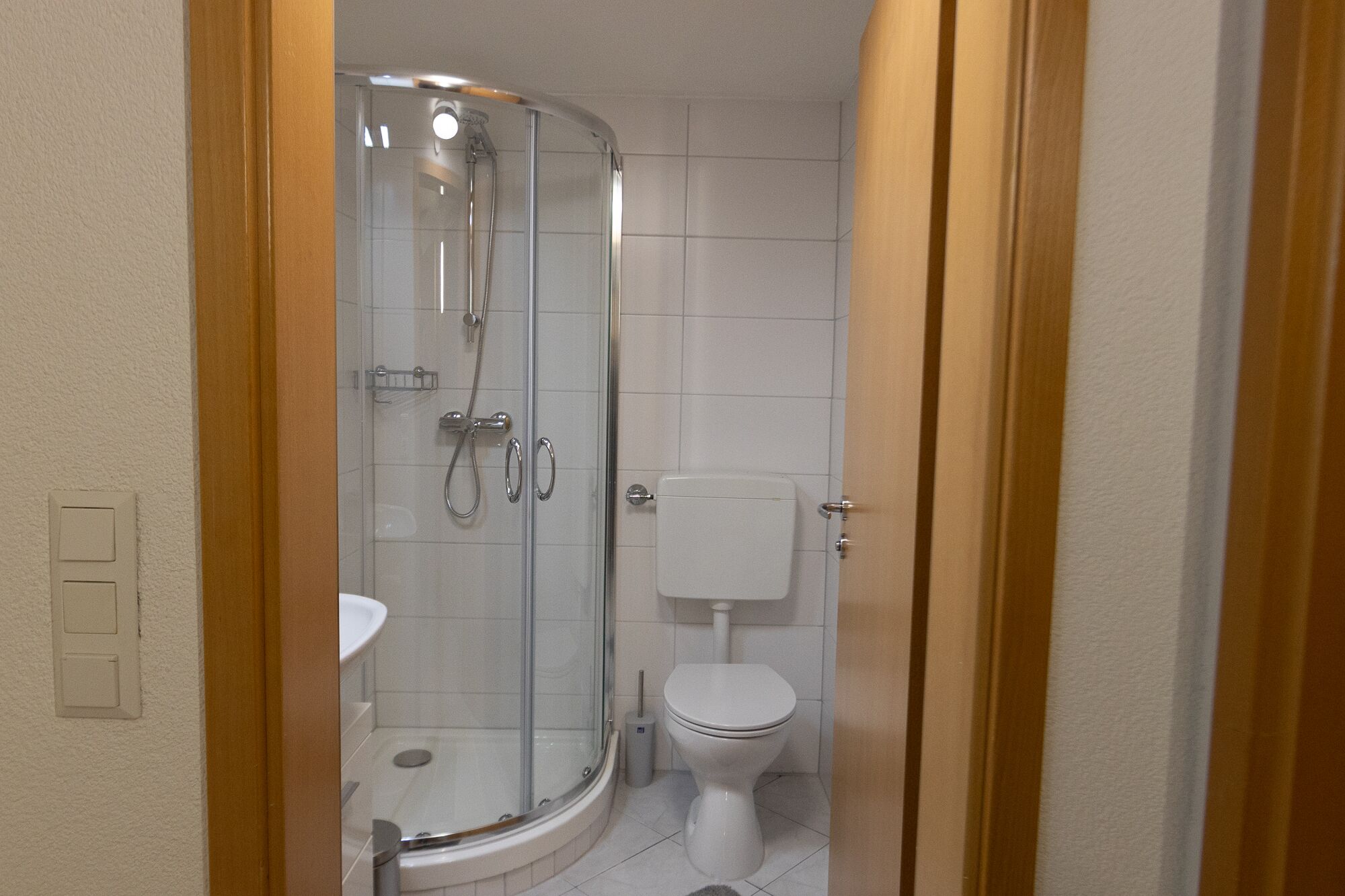A bathroom with a glass-enclosed shower, a toilet, and a sink.