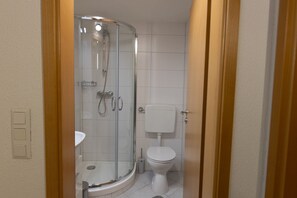 Une salle de bain avec une douche à parois de verre, des toilettes et un lavabo.